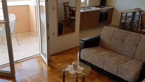 Un salon comprenant un canapé, une table basse en verre agrémentée d’un objet décoratif, et un coin repas avec une chaise et une table.