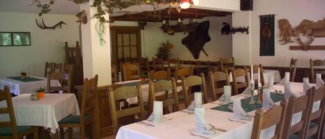 Un restaurante con mesas y sillas de madera, decorado con cuernos de ciervo y una araña.