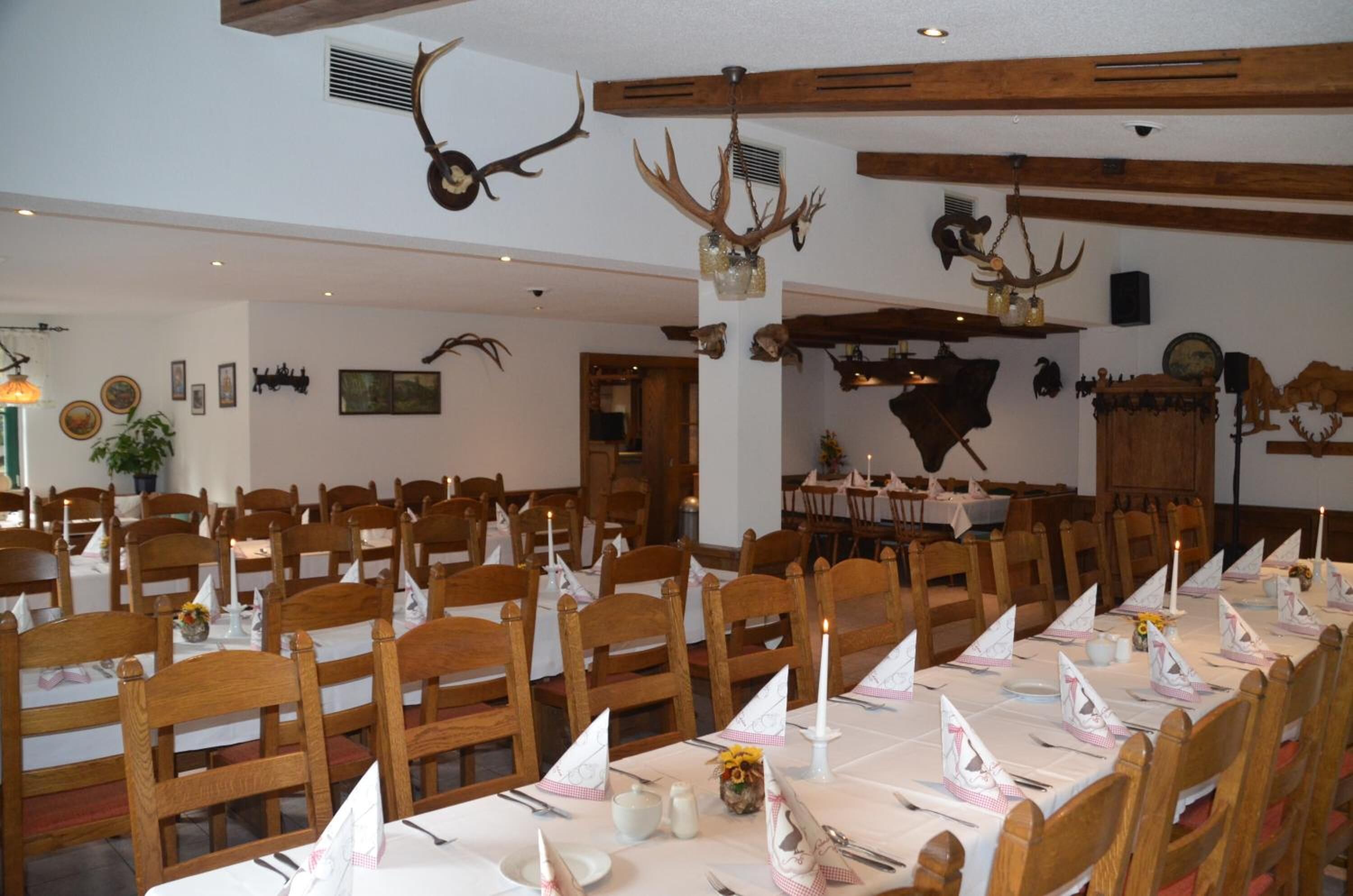 Un comedor con mesas y sillas de madera, decoraciones de asta de ciervo y un cráneo de vaca en la pared.