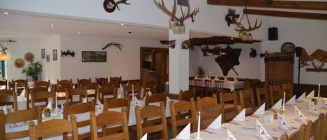 Un comedor con mesas y sillas de madera, decoraciones de asta de ciervo y un cráneo de vaca en la pared.
