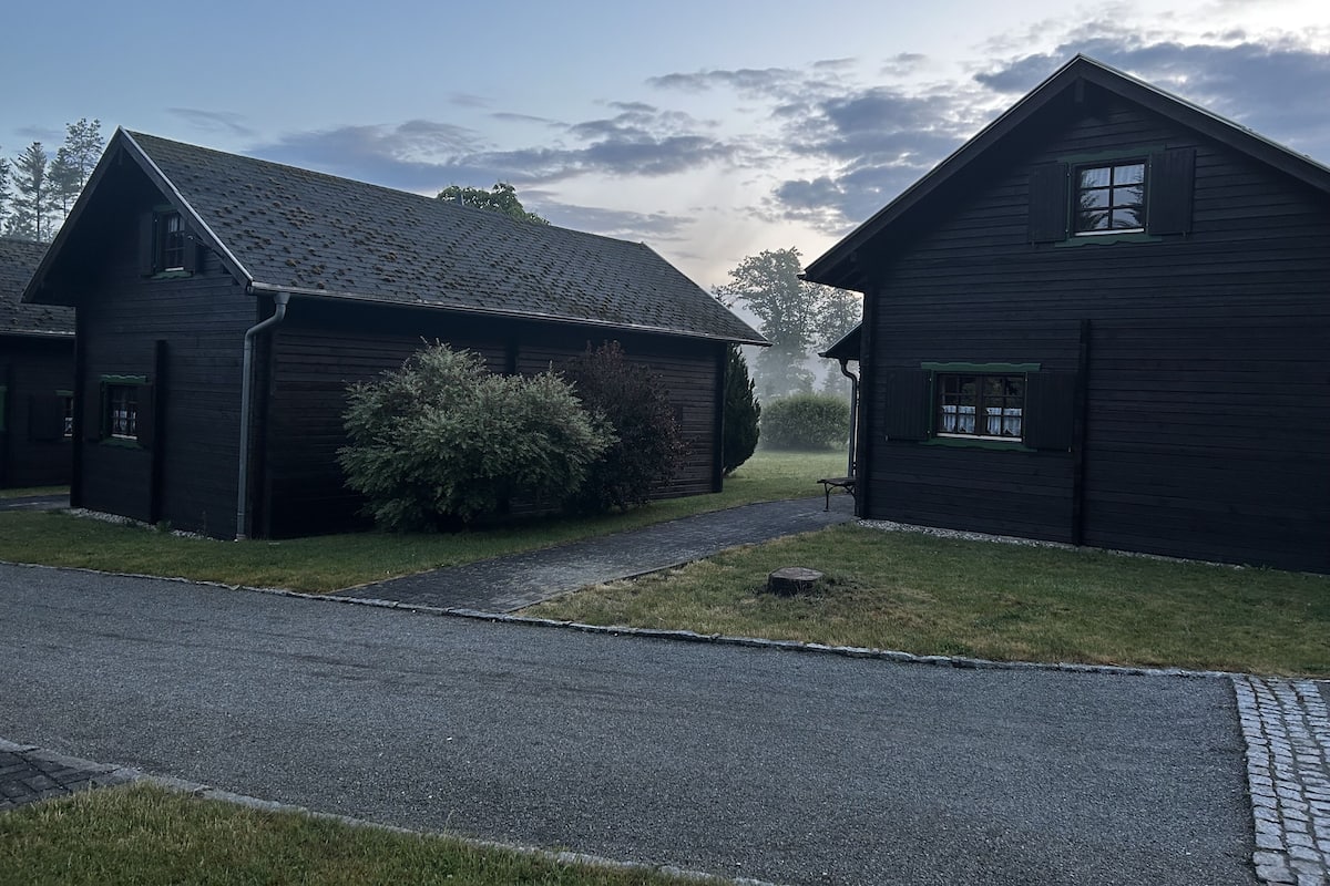 Een zwart houten gebouw met schuin dak, klein raam en een deur.