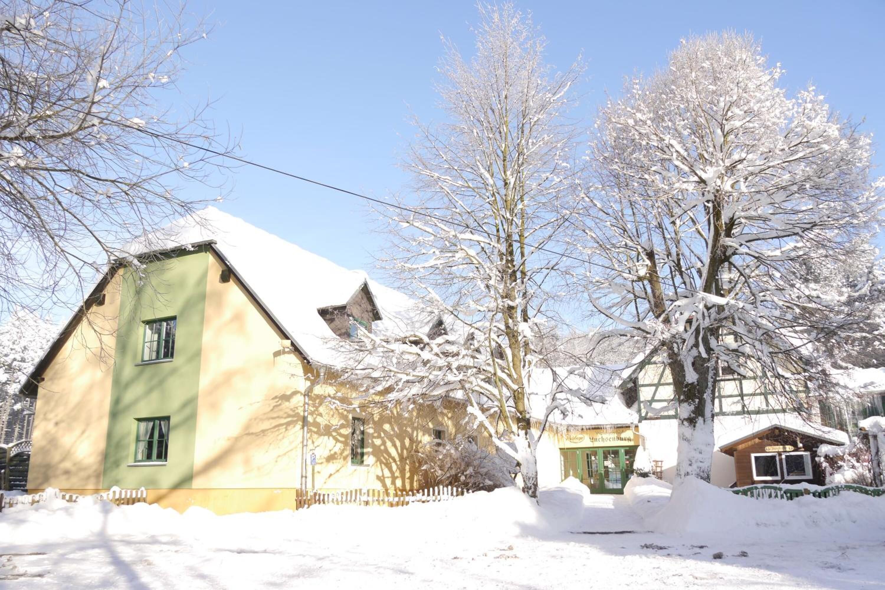A two-story building with a green facade and a snow-covered roof.