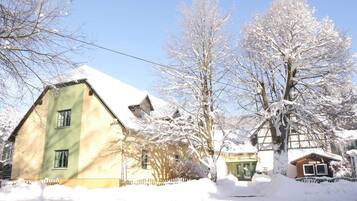 A two-story building with a green facade and a snow-covered roof.