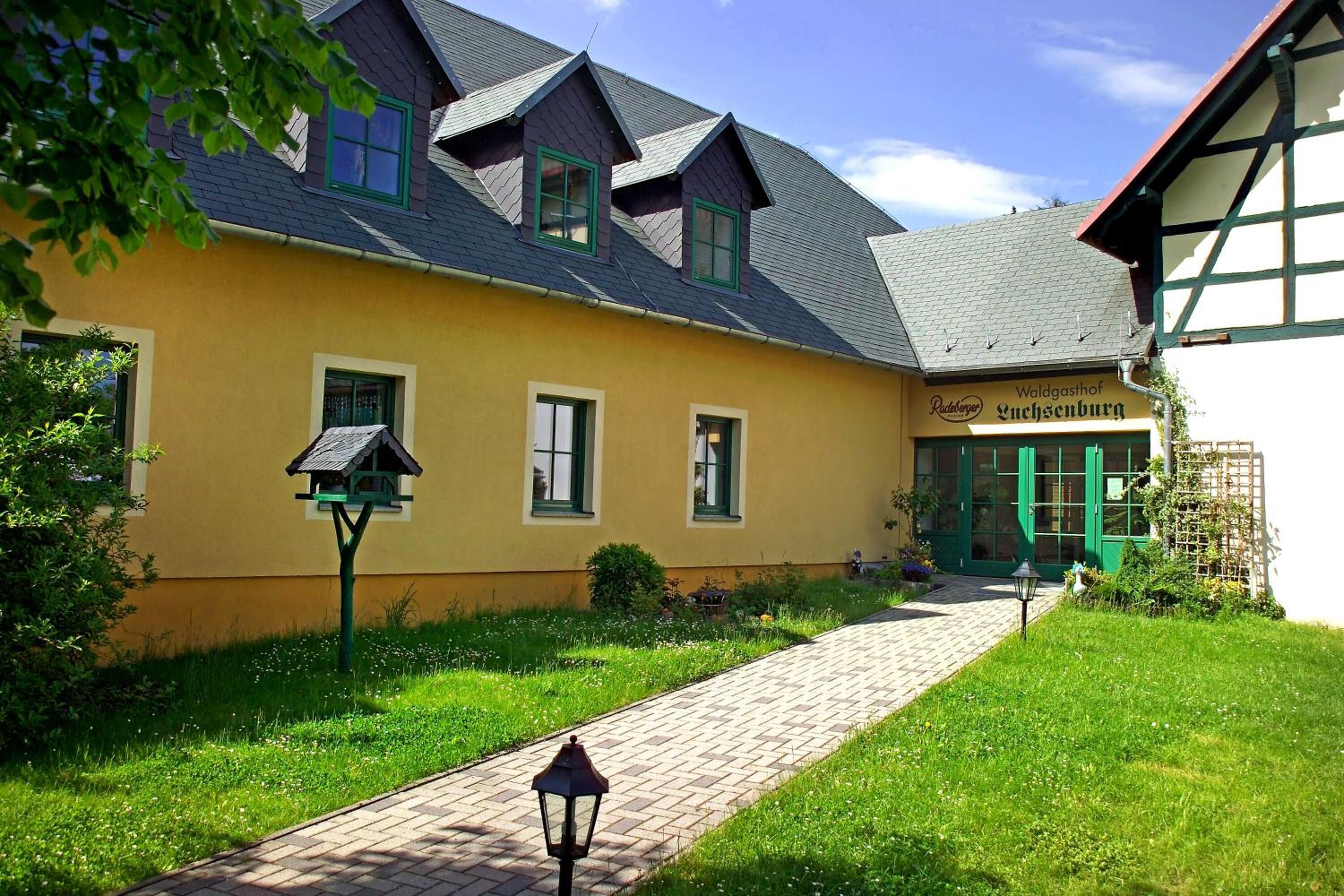 Un edificio giallo con un cartello che riporta la scritta "Waldgasthof Wuchsenburg".