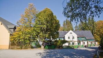 A traditional building with a green roof and white walls, surrounded by trees and a fence.