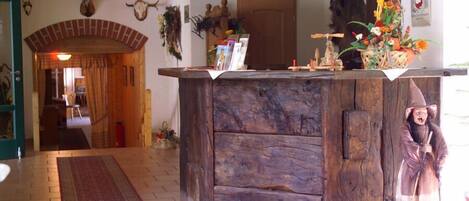 A rustic interior with a wooden reception desk, a decorative cow skull, and a statue of a witch.