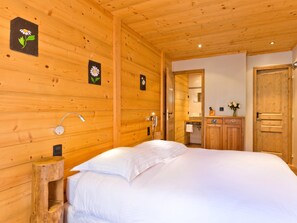 Une pièce en bois avec un lit, une armoire en bois, un miroir et un luminaire fixé au mur.