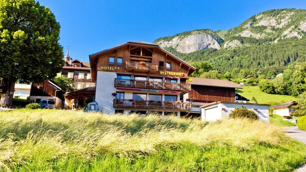 Ein Hotel mit Restaurant im zweiten Stock, umgeben von üppiger Vegetation und Bergen.