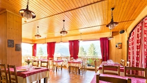 A restaurant with wooden interiors, red curtains, and tables set for dining. - Logis Hotel L'accueil Savoyard (Mieussy)