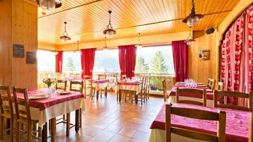 Un restaurante con interiores de madera, cortinas rojas y mesas dispuestas para comer.