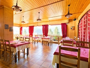 A restaurant with wooden interiors, red curtains, and tables set for dining. - Logis Hotel L'accueil Savoyard (Mieussy)