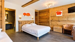 Ein Schlafzimmer mit Holzboden, einem Bett, einem Sessel und einem an der Wand befestigten Fernseher.