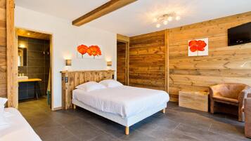 Un dormitorio con techo de madera, una cama, una silla y un televisor fijado a la pared.