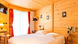 Ein Zimmer in einer Holzhütte mit einem Bett, einem Schreibtisch und einem Stuhl.