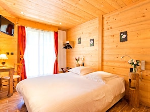 A wooden cabin room with a bed, a desk, and a chair. - Logis Hotel L'accueil Savoyard (Mieussy)