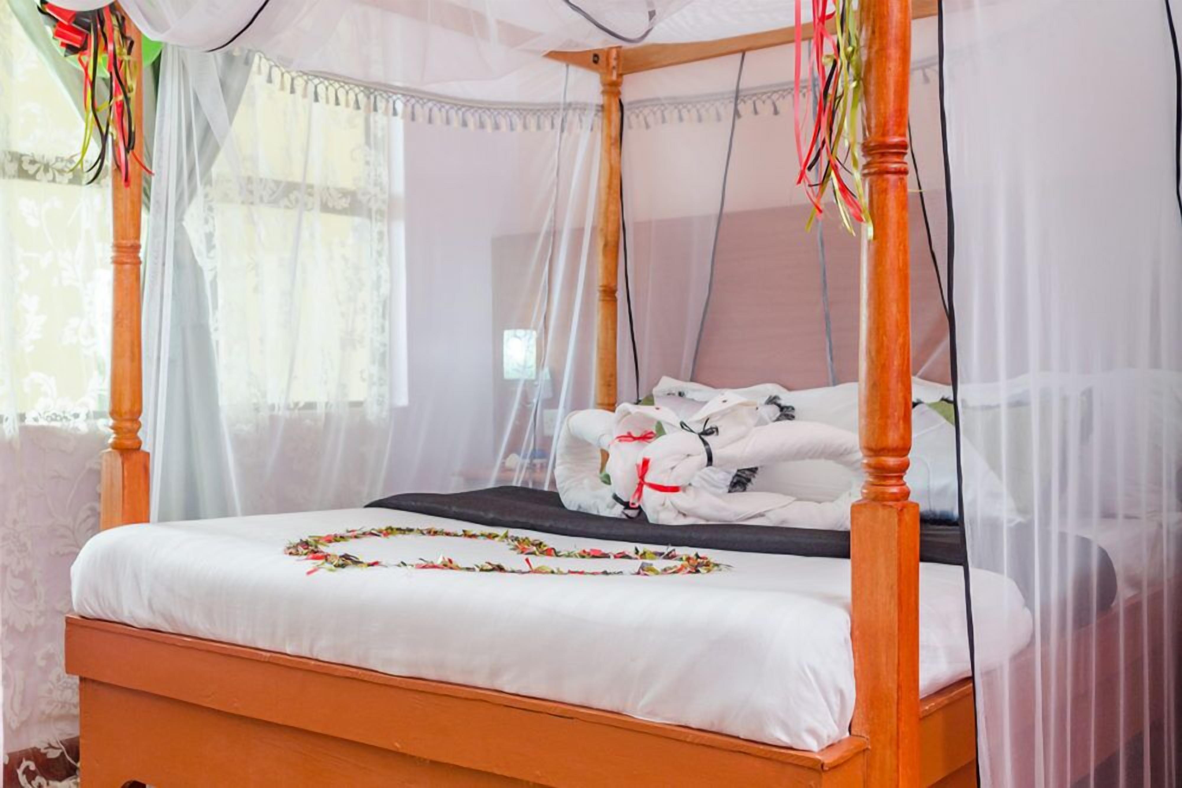 A four-poster bed with a canopy, white bedding, and a decorative garland.