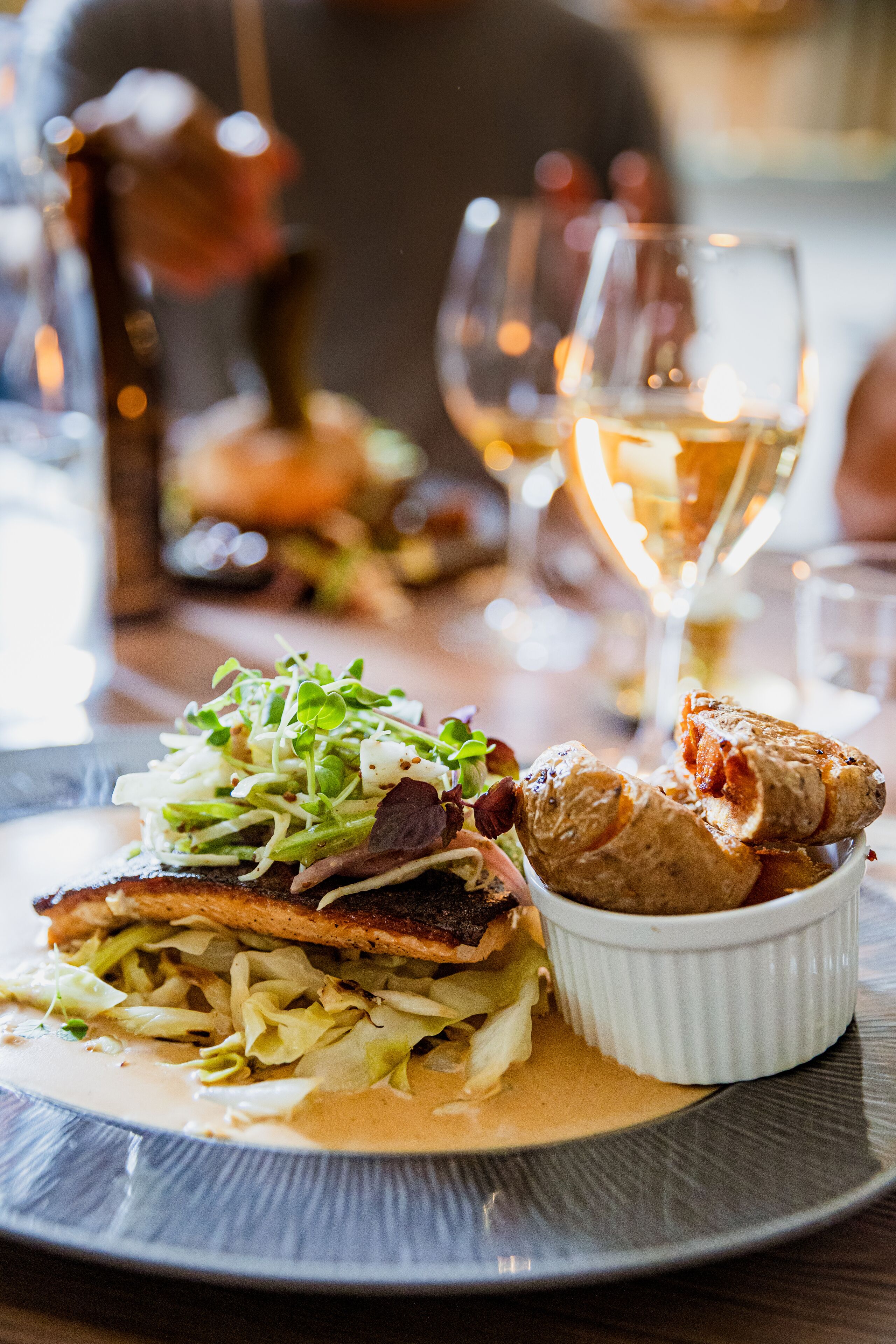 A plate of food with a salad, a piece of meat, and a small bowl of sauce.