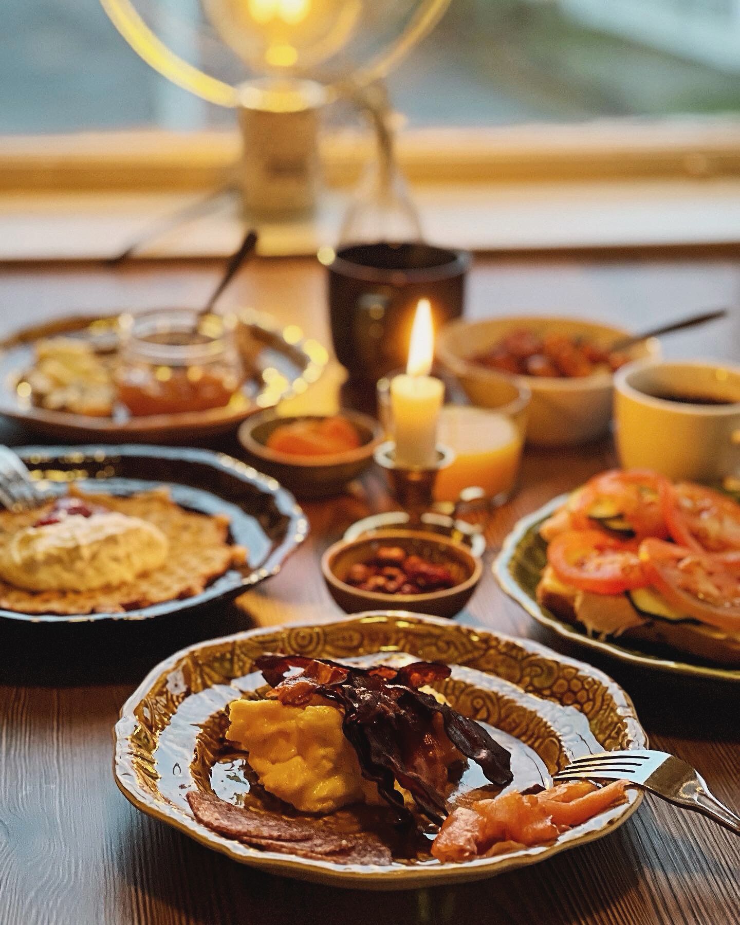 A table with various dishes, a candle, and a window in the background.