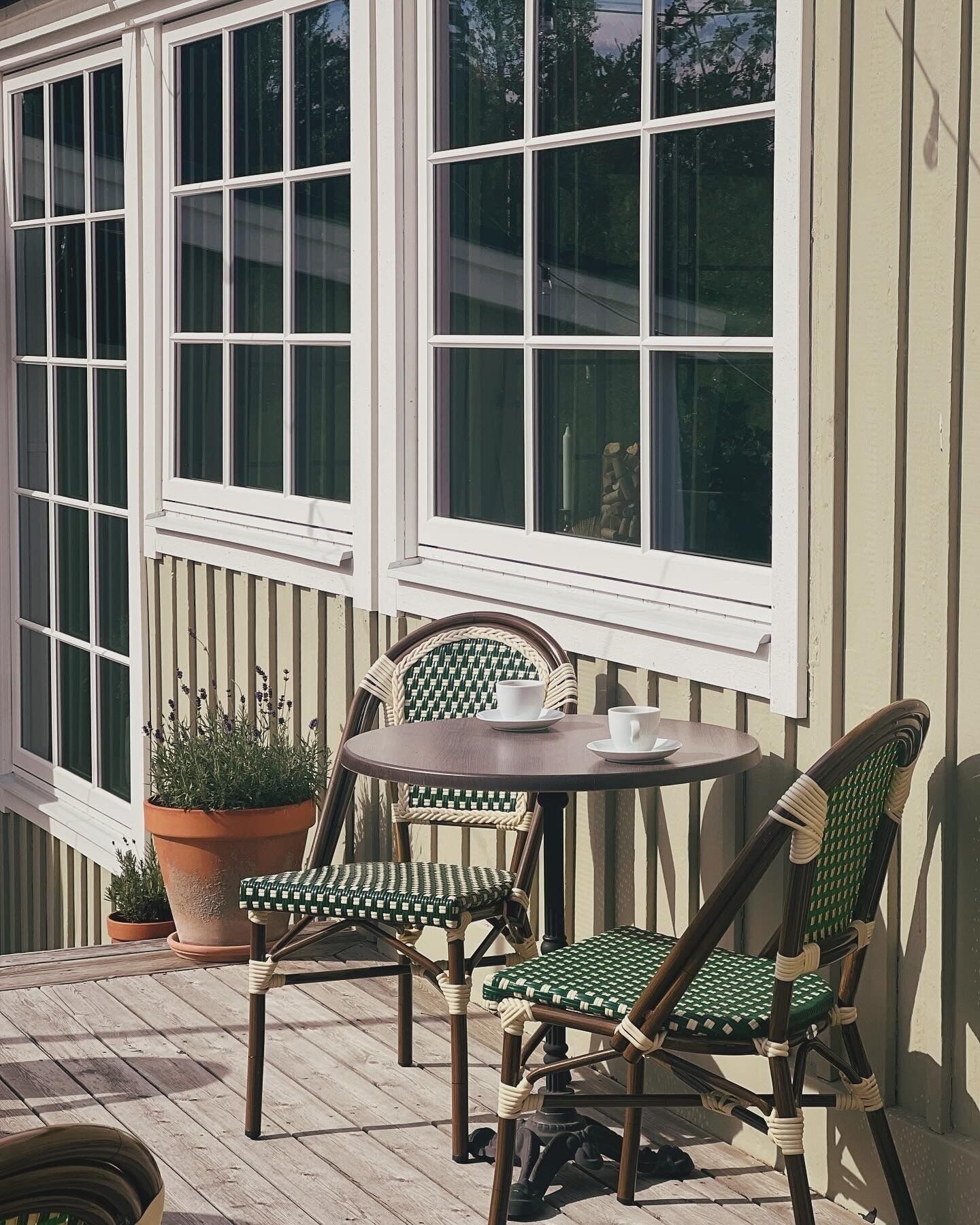 A patio with a table and chairs, a potted plant, and a window with white shutters.