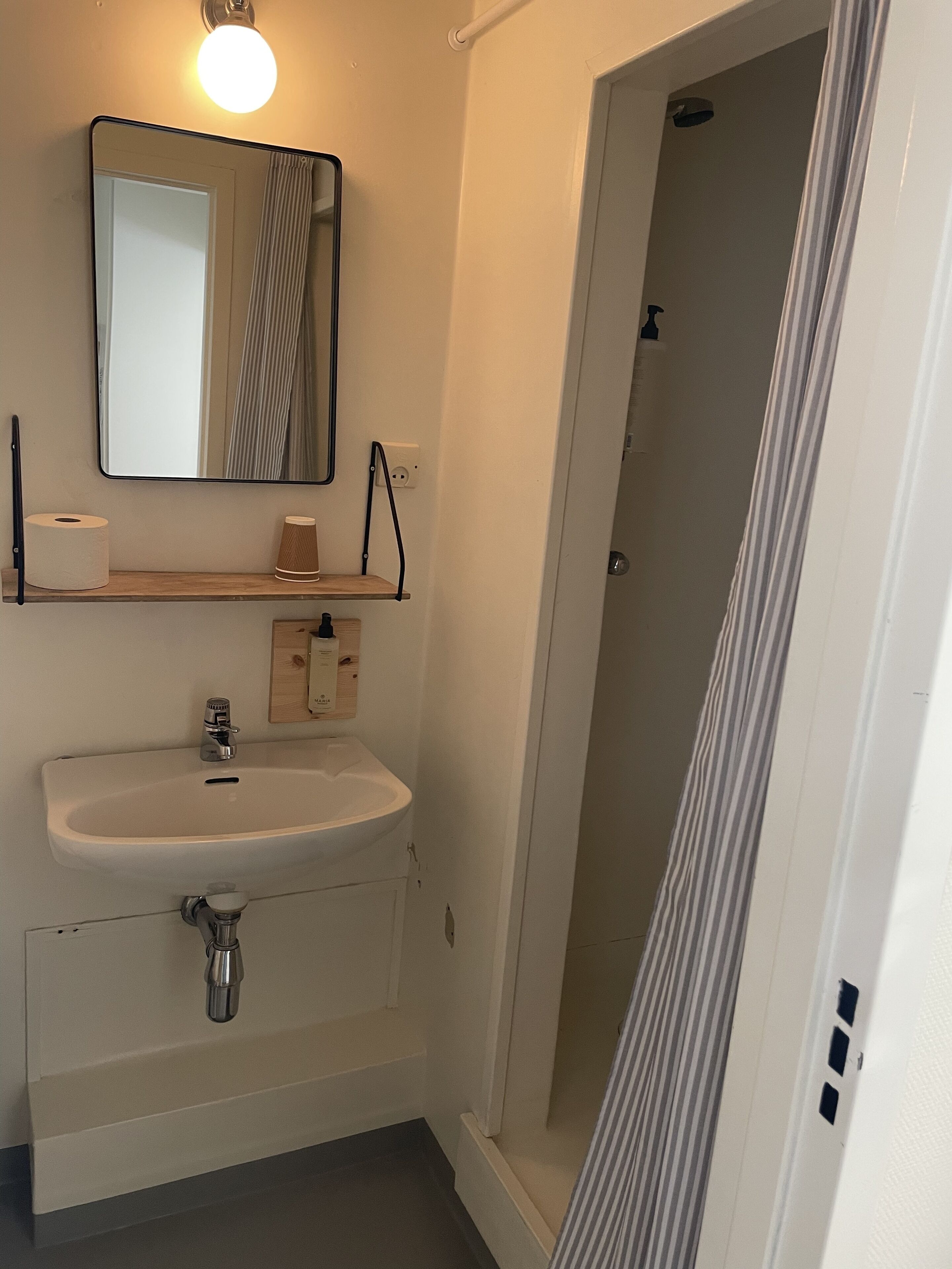A bathroom with a sink, mirror, and shower.