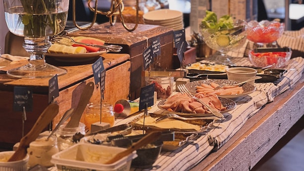 Una mesa de buffet con diversos alimentos, un jarrón con flores y velas.