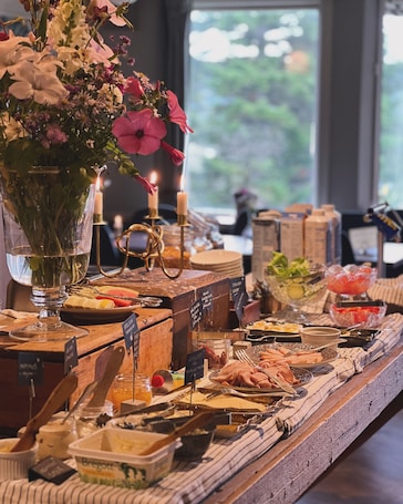 A buffet table with various food items, a vase with flowers, and candles.