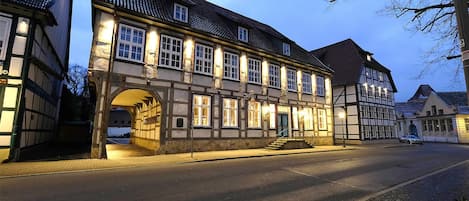 Ein traditionelles europäisches Gebäude mit einem zentralen Bogen, zahlreichen Fenstern und einer gepflasterten Straße davor.