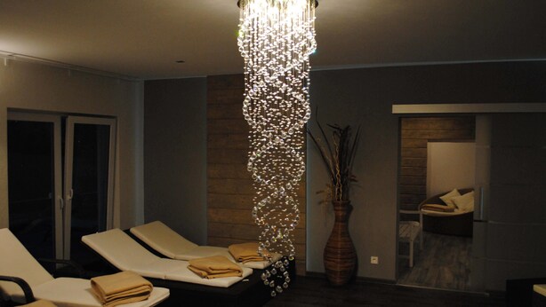 Ein moderner Raum mit einer Chandelüstere, Lounge-Stühlen und einer großen Vase.