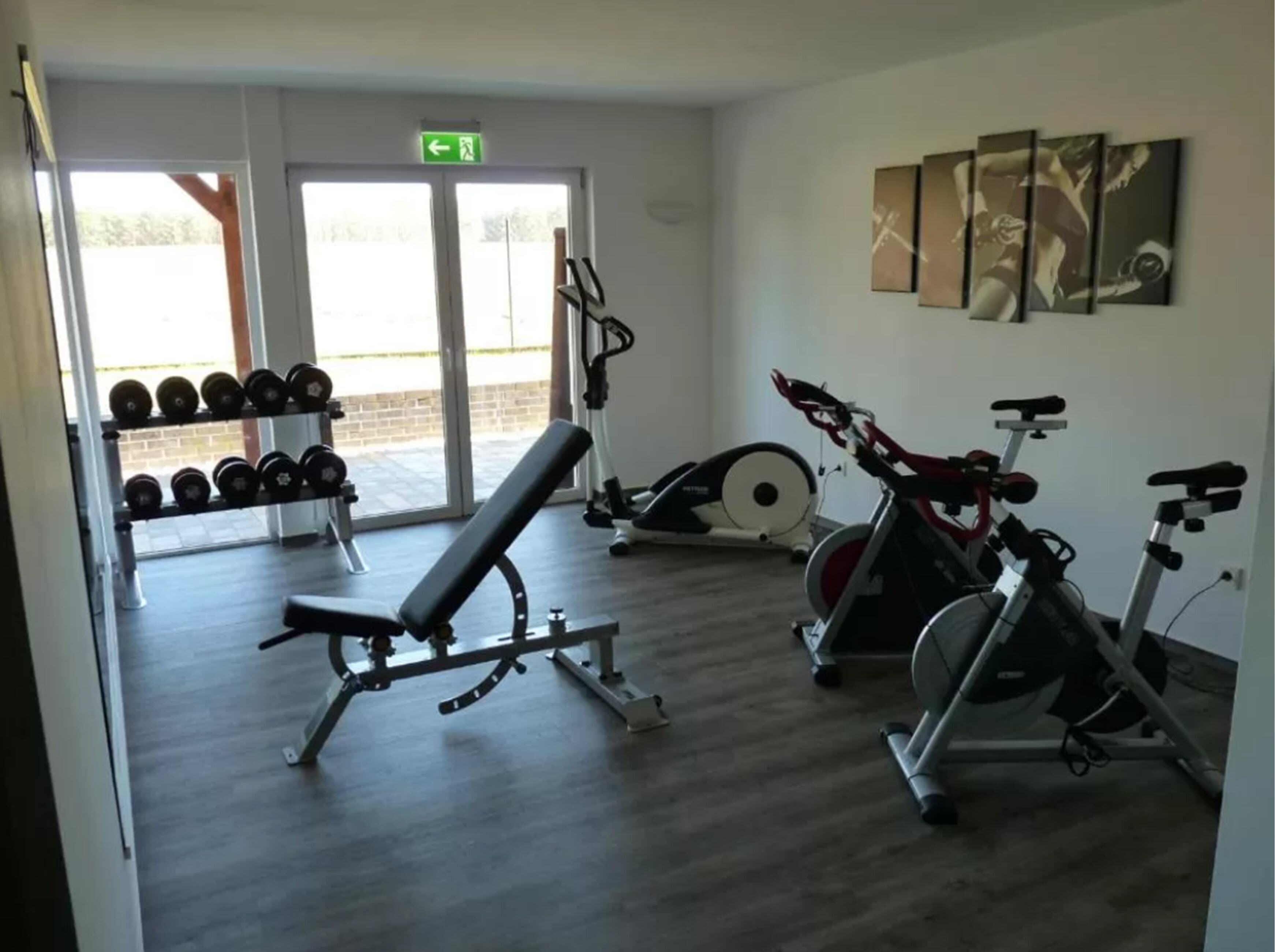 Ein Fitnessstudio mit Bänken, Kurzhanteln und Cardiogeräten.