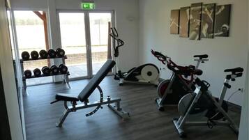 Ein Fitnessstudio mit Bänken, Kurzhanteln und Cardiogeräten.