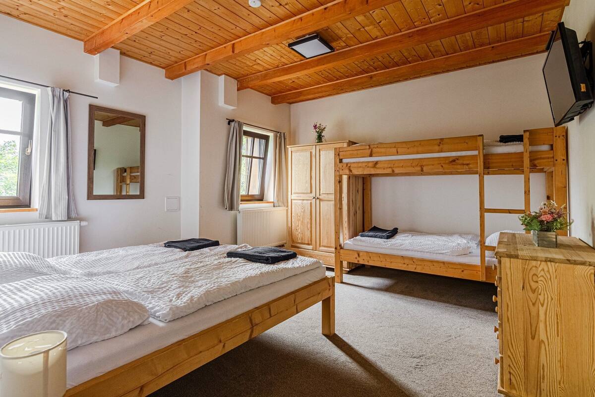 A room with two bunk beds, a wooden wardrobe, a mirror, and a window with curtains.