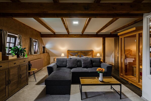 A cozy living room with a sectional sofa, a wooden coffee table, and a large window with curtains.