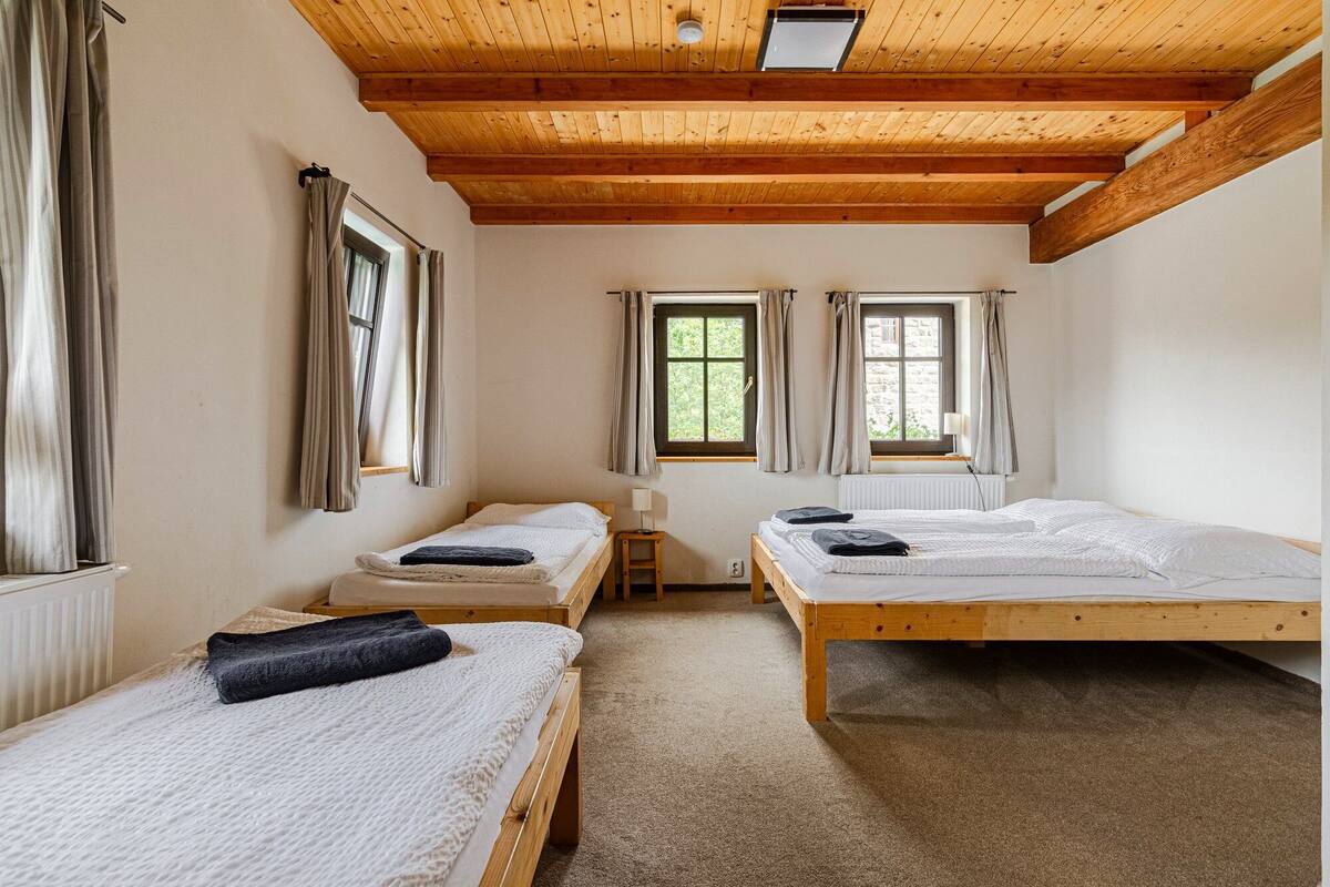 A room with two wooden beds, a small table, and a window with curtains.