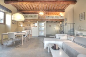 A spacious living area with a high ceiling, a dining table with chairs, a sofa, and a bench. - Agriturismo Il Poderaccio (Scandicci)