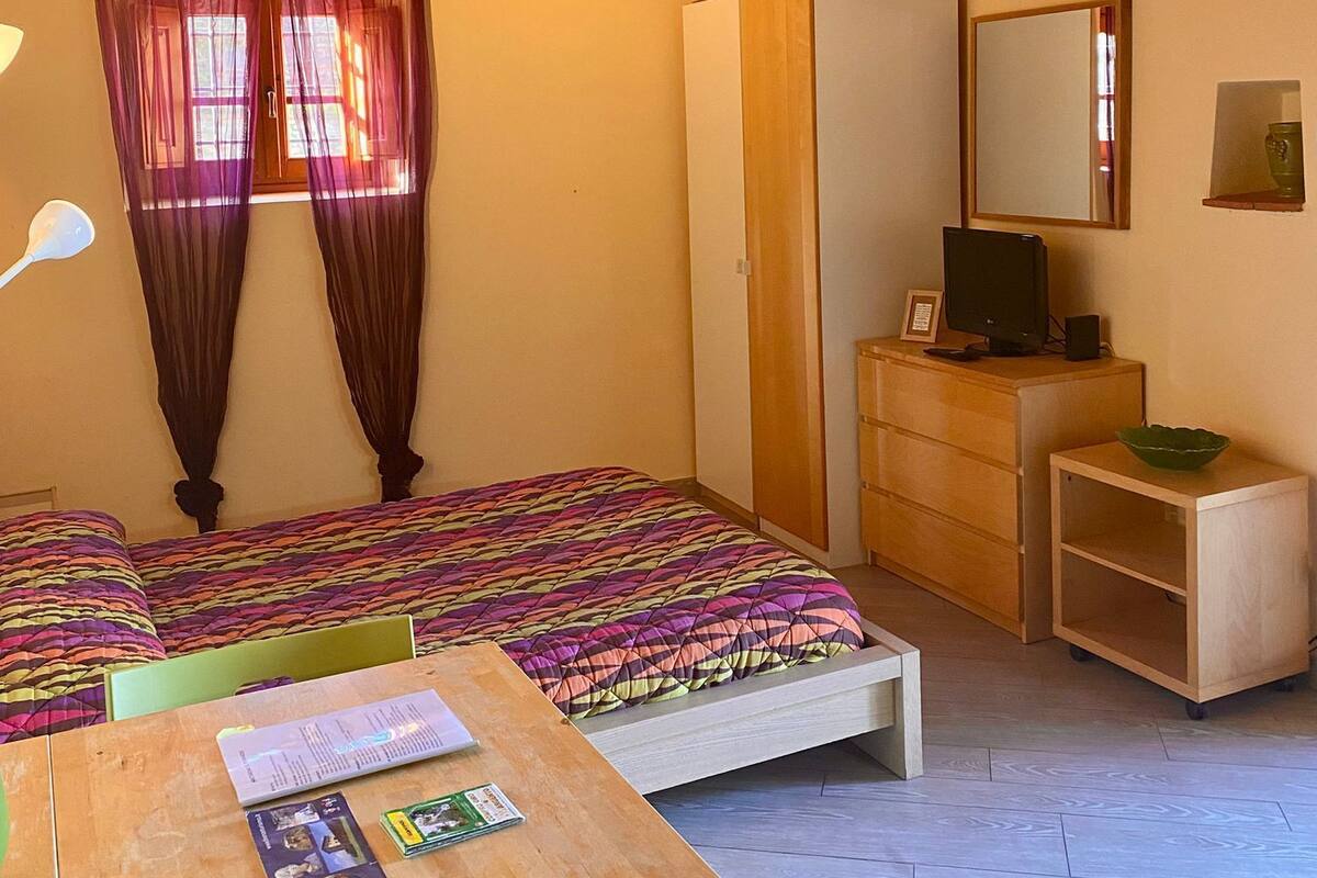 Un dormitorio con cama, escritorio de madera, cómoda, espejo y aire acondicionado.