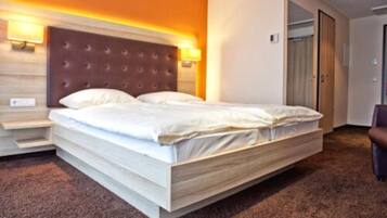 A hotel room with a large bed, a headboard with a tufted design, and a carpeted floor.