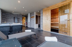 Un moderno espacio de spa con camilla de masaje, zona de estar y sauna.