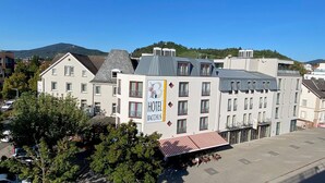 A hotel with a prominent 'HOTEL BACCUS' sign, multiple balconies, and a parking area. - Bacchus Hotel (Bensheim)