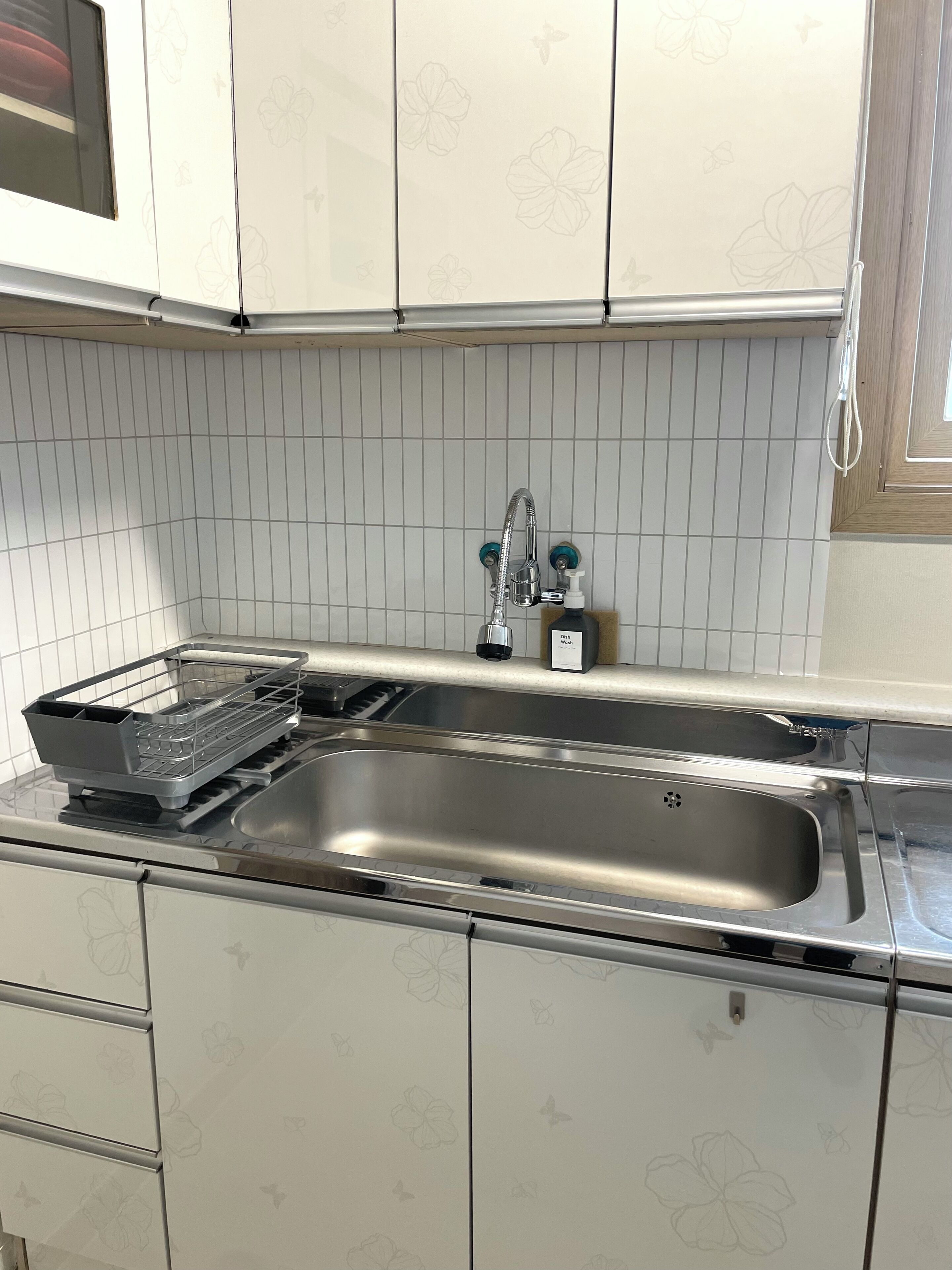 Una cocina con un lavamanos de acero inoxidable, un escurreplatos y un grifo.