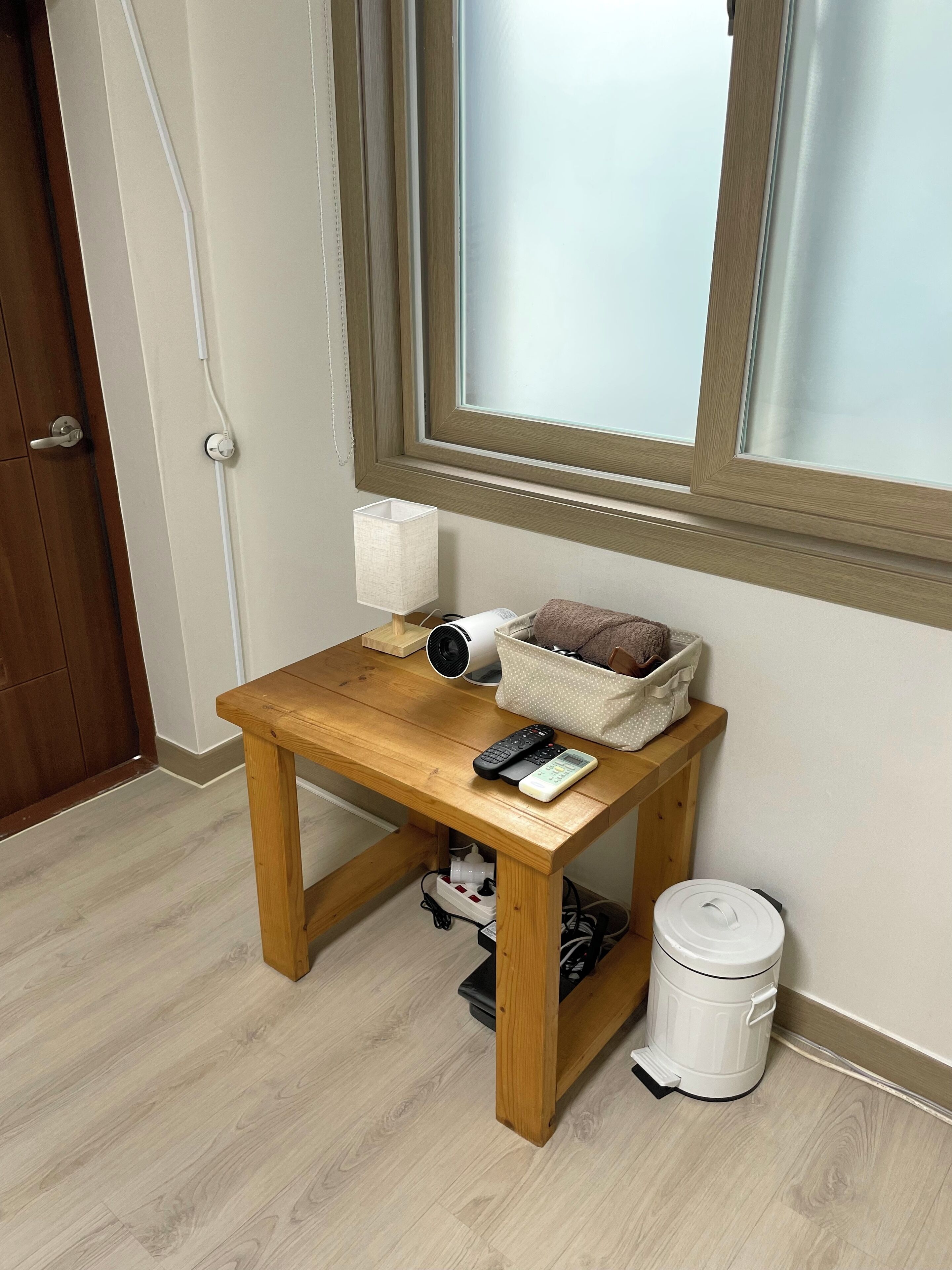 A small wooden table with a lamp, a speaker, and a remote control.