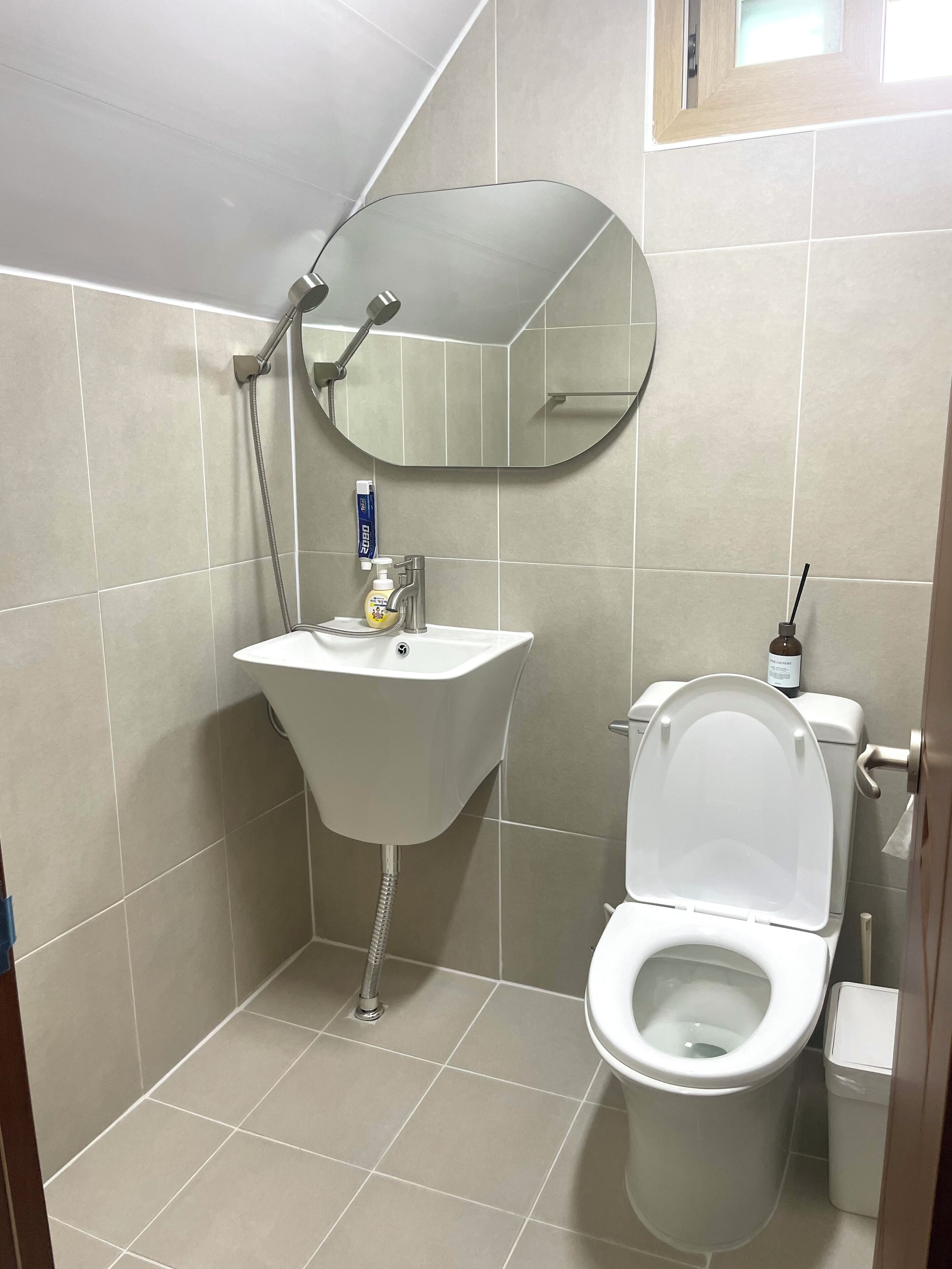 A small bathroom with a toilet, sink, and a mirror.