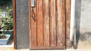 Una puerta de madera con un letrero azul que indica 'Hyunggyo-gil 11'.