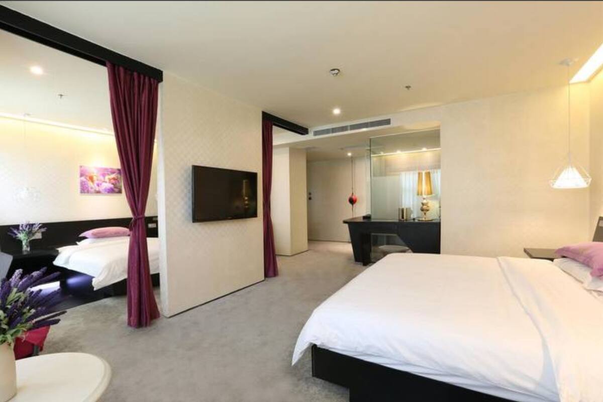 Una habitación de hotel moderna con una cama grande, un escritorio, un espejo y un televisor.