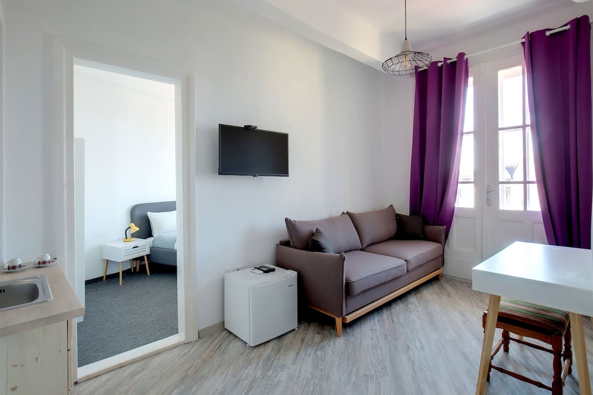 A modern living room with a grey sofa, a white table, and a TV mounted on the wall.