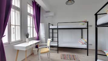 Habitación tipo dormitorio con literas, un escritorio, una silla, una alfombra pequeña y una lámpara colgante.