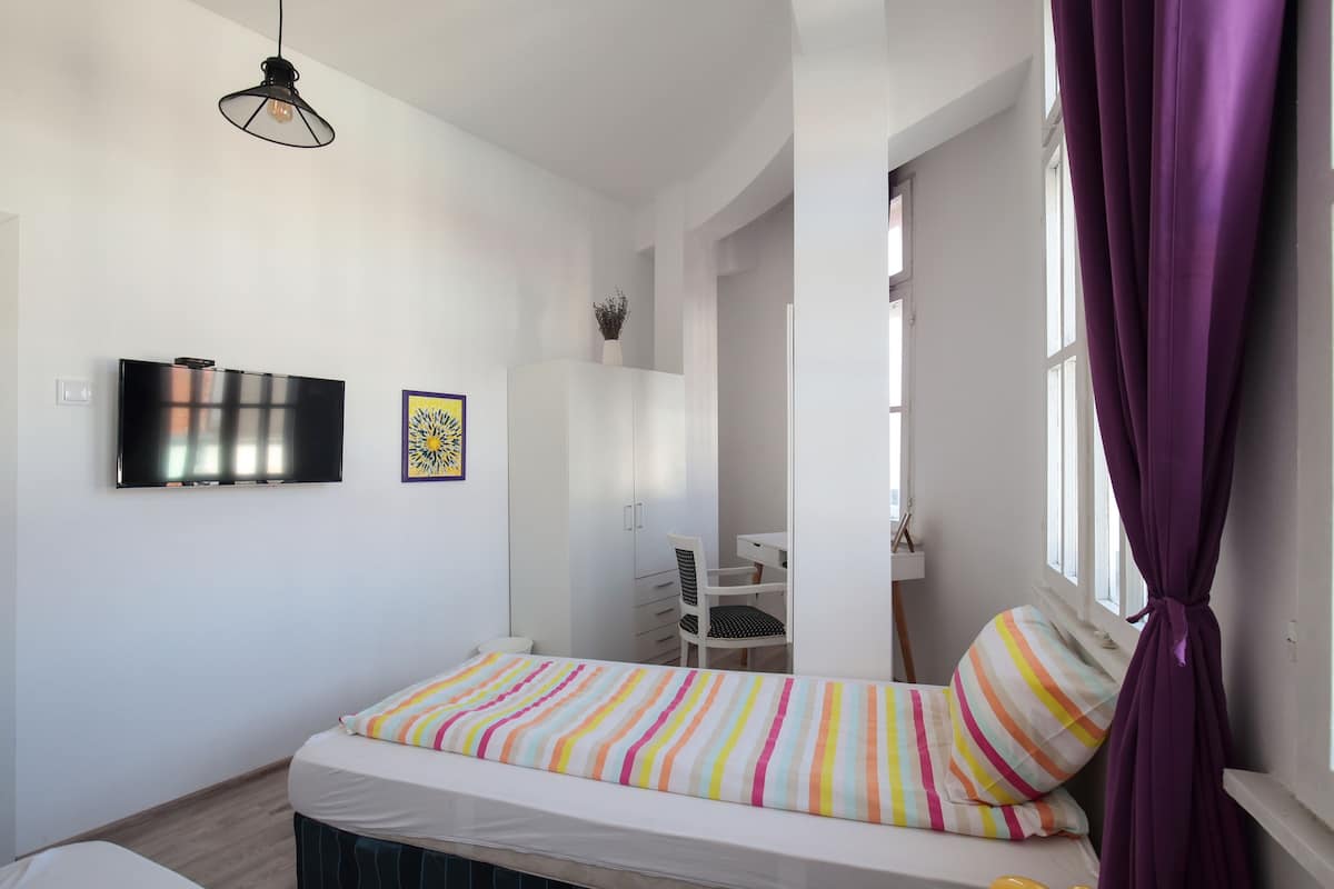 A bedroom with a bed, a TV, a desk, and a chair.