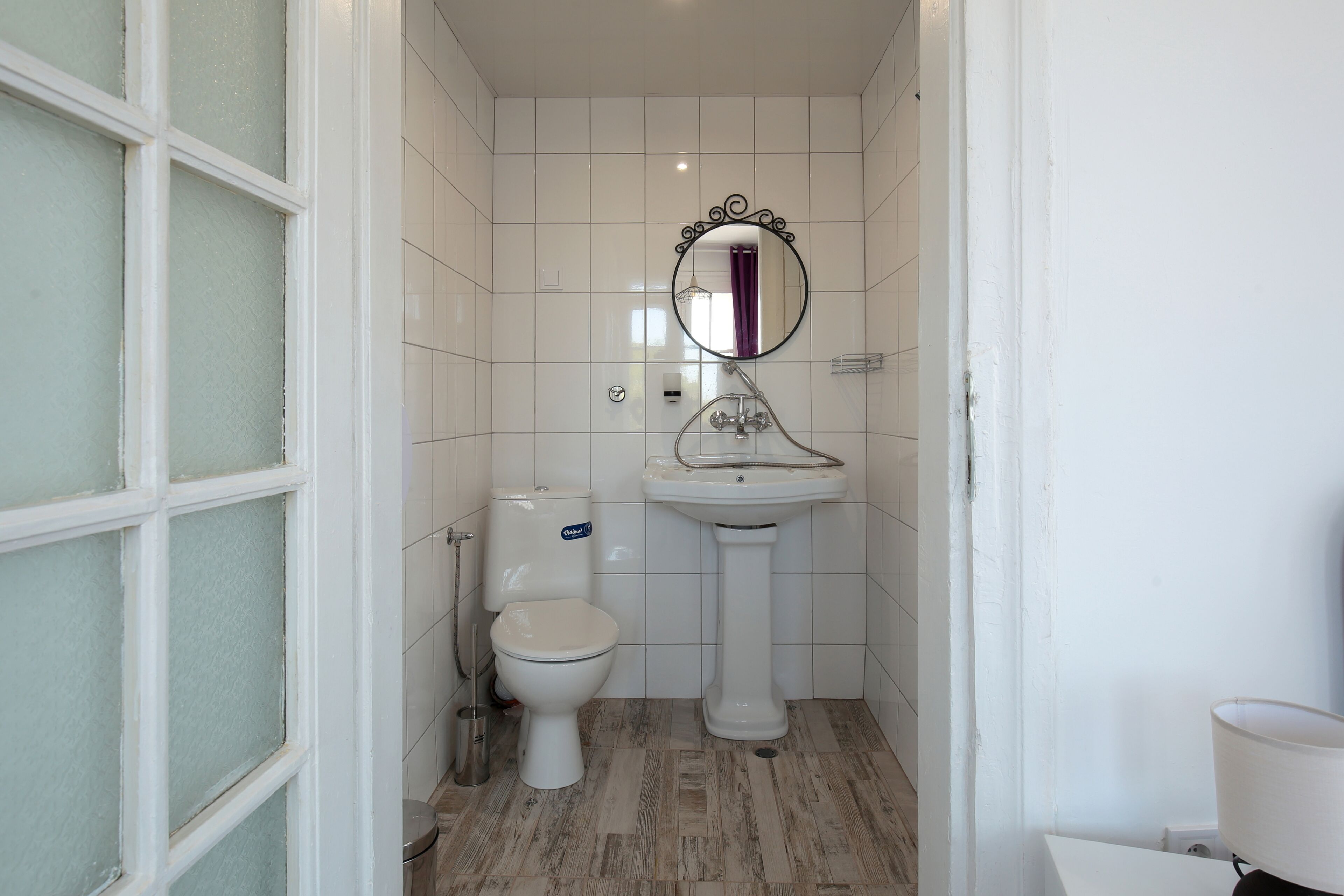 A bathroom with a toilet, sink, and mirror.