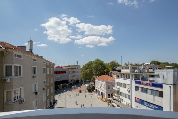 Una plaza pública con edificios, incluyendo un Postbank y un edificio con un letrero en escritura cirílica.