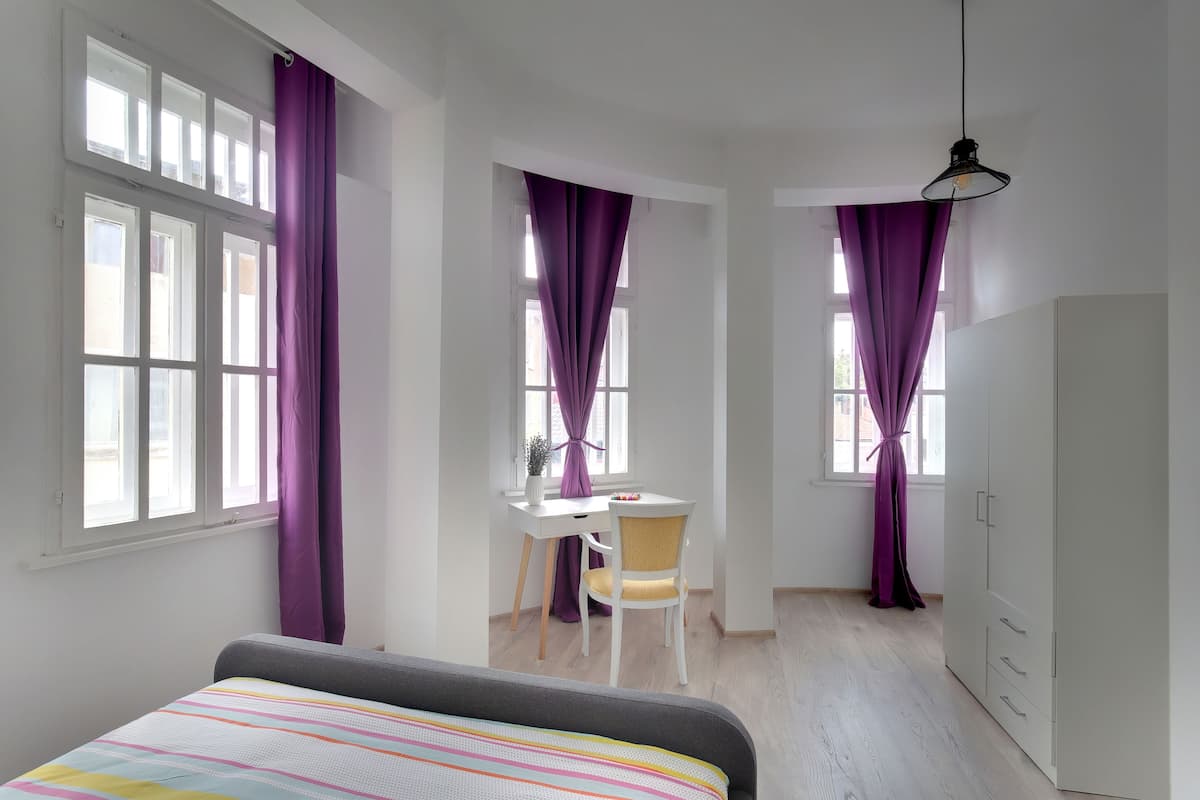 A bedroom with a bed, a desk, a chair, and a wardrobe.