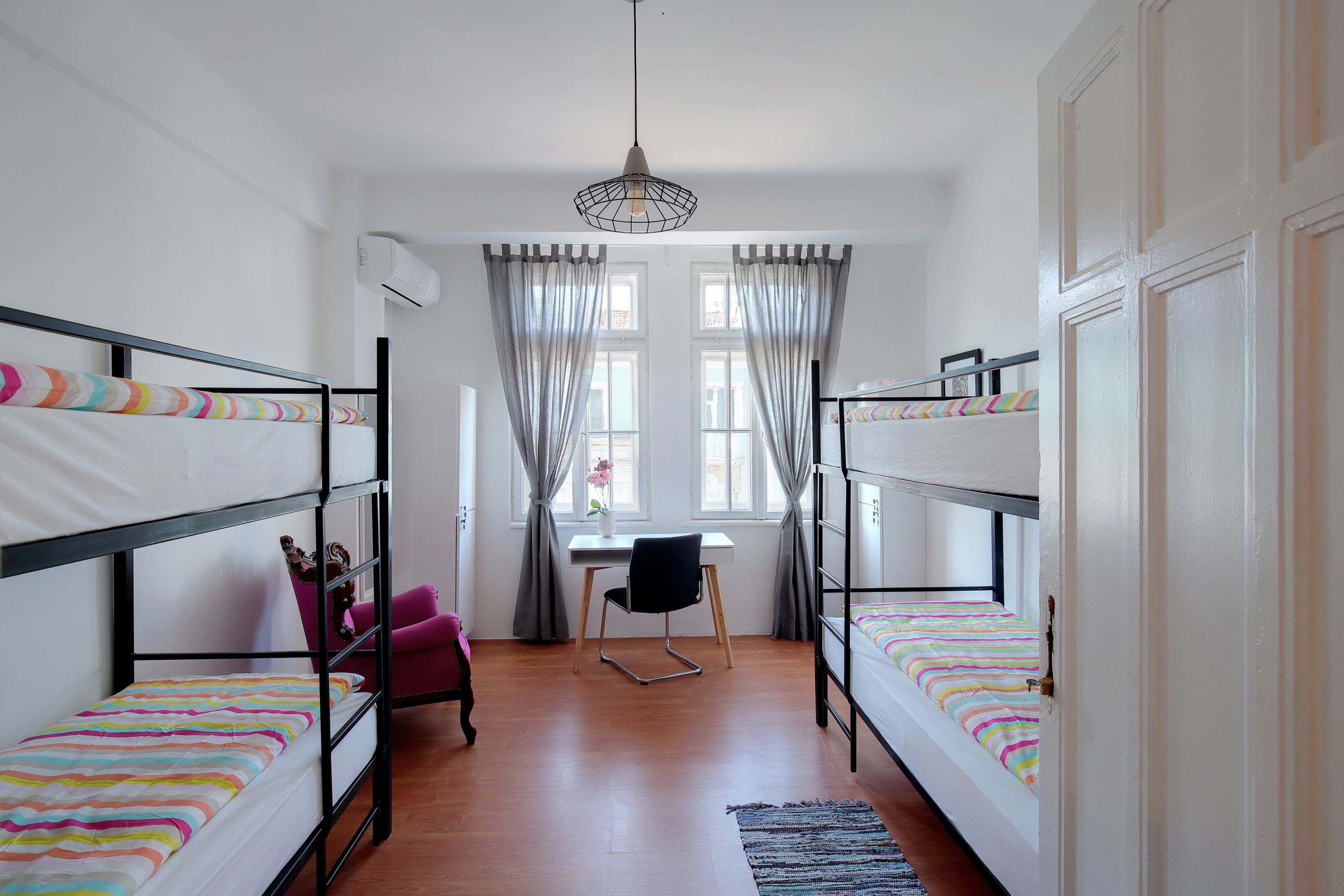 A dormitory room with bunk beds, a desk, and a chair.